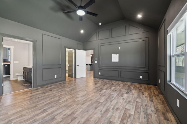 interior space featuring lofted ceiling, ceiling fan, a decorative wall, and wood finished floors