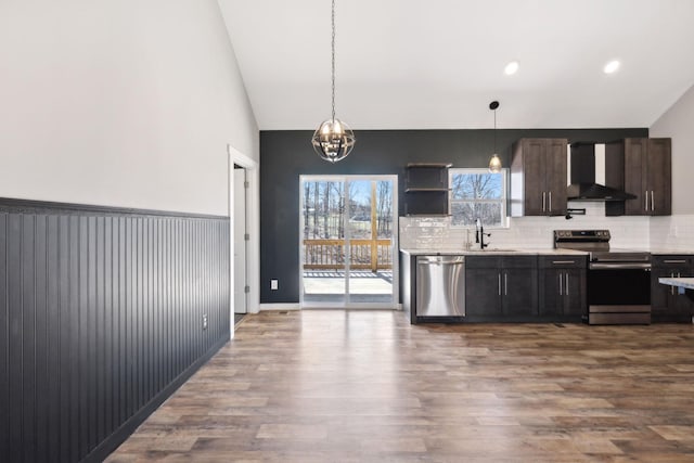 kitchen featuring stainless steel appliances, dark wood-style flooring, a sink, wall chimney range hood, and decorative backsplash