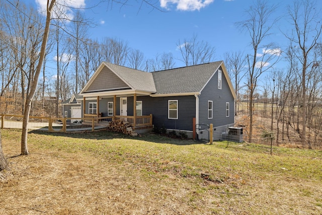 view of front of house with covered porch, roof with shingles, fence, and a front yard