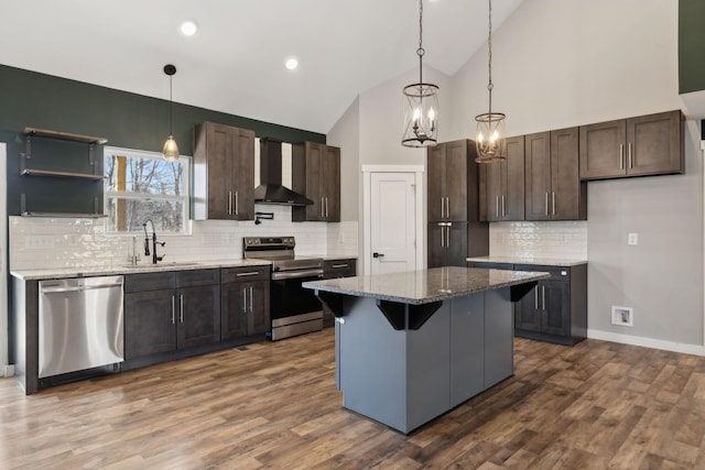 kitchen featuring dark wood-style floors, appliances with stainless steel finishes, a sink, dark brown cabinets, and wall chimney exhaust hood