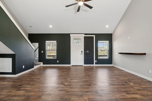 unfurnished living room featuring stairs, vaulted ceiling, wood finished floors, and a wealth of natural light