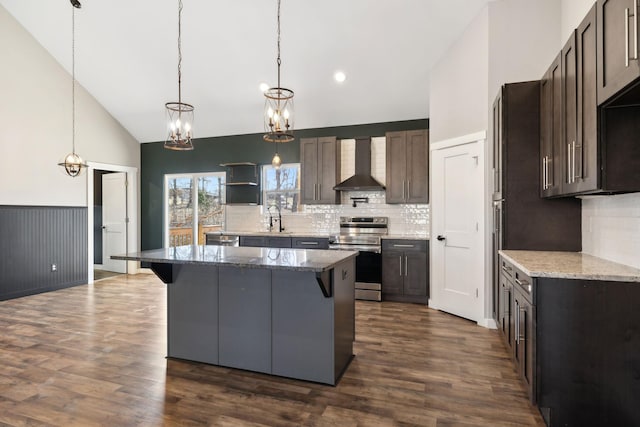 kitchen featuring dark wood finished floors, a breakfast bar area, stainless steel range with electric cooktop, wall chimney range hood, and a sink