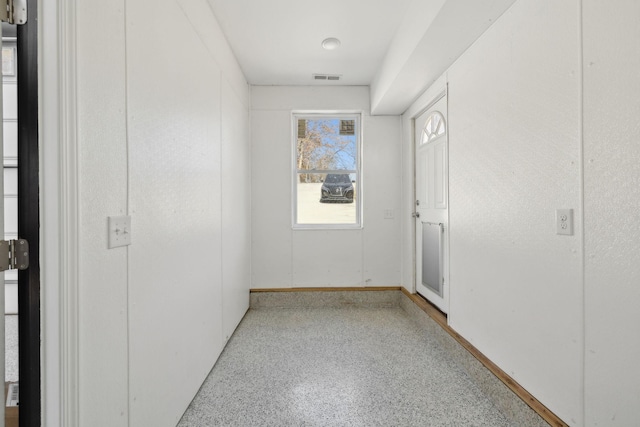 spare room featuring baseboards, visible vents, and speckled floor