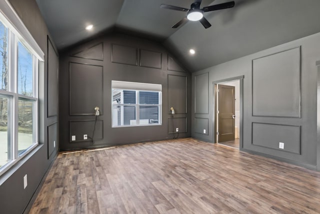 interior space with lofted ceiling, ensuite bath, a decorative wall, and wood finished floors