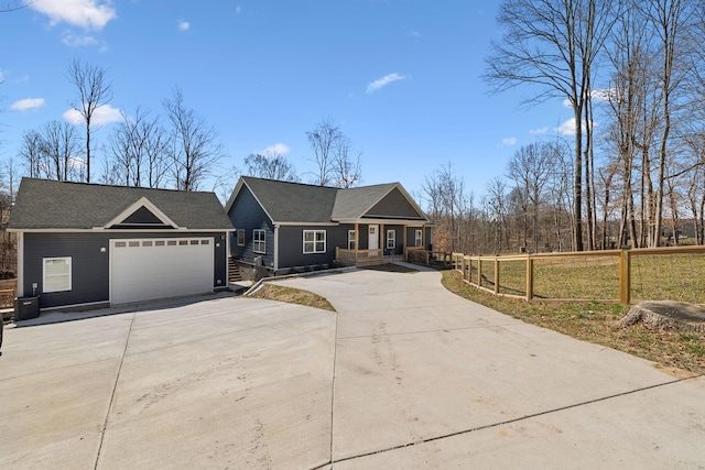 view of front of property featuring driveway, a fenced front yard, a garage, and cooling unit