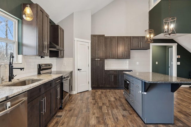 kitchen featuring dark wood-style flooring, stainless steel appliances, stone countertops, a sink, and wall chimney range hood