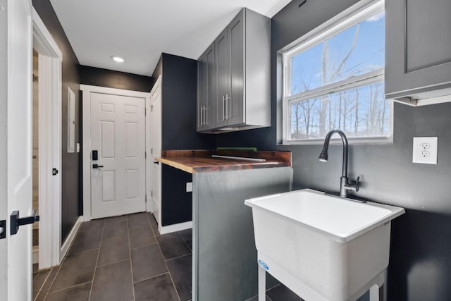 kitchen with gray cabinetry, baseboards, a sink, and dark tile patterned flooring