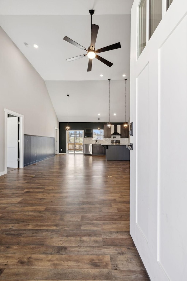 unfurnished living room featuring high vaulted ceiling, dark wood finished floors, and a ceiling fan