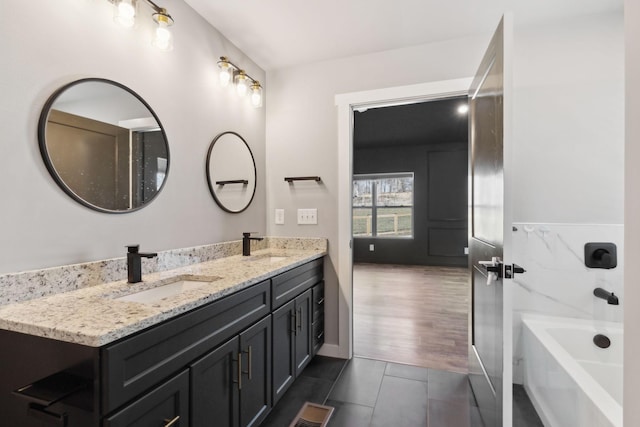 full bath featuring tile patterned floors, a sink, a bathing tub, and double vanity