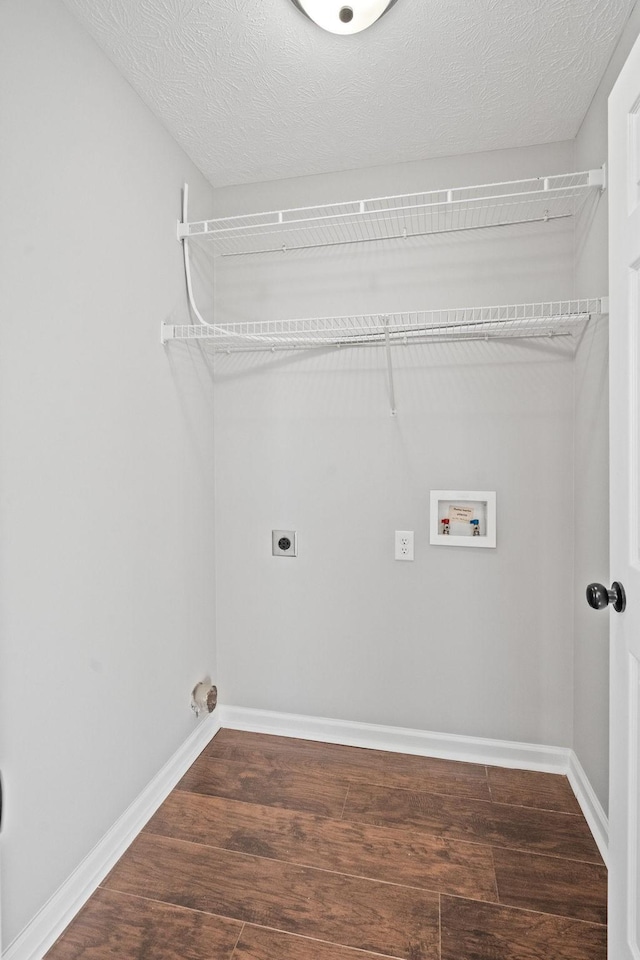 washroom featuring baseboards, wood finished floors, hookup for a washing machine, a textured ceiling, and electric dryer hookup