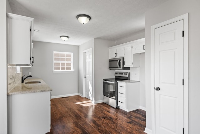 kitchen featuring stainless steel appliances, a sink, white cabinets, tasteful backsplash, and dark wood finished floors