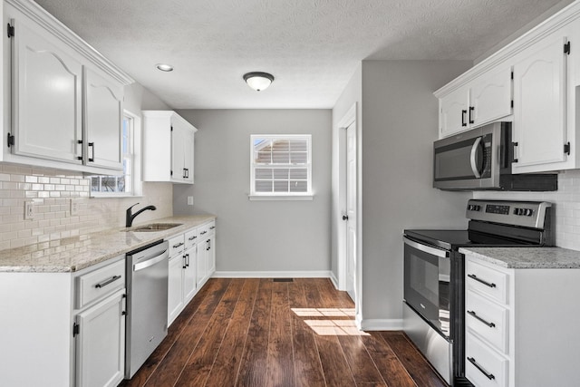 kitchen with dark wood-style flooring, a sink, baseboards, white cabinets, and appliances with stainless steel finishes