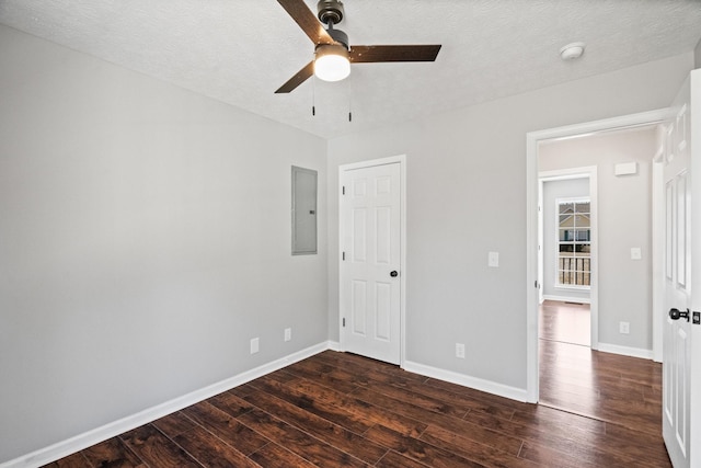 unfurnished bedroom with dark wood-style floors, electric panel, baseboards, and a textured ceiling