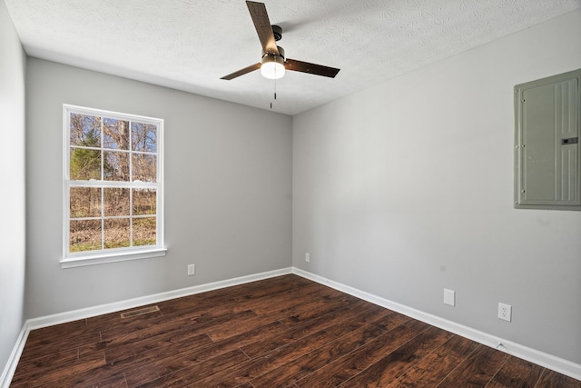 spare room featuring dark wood-style flooring, electric panel, a textured ceiling, and baseboards