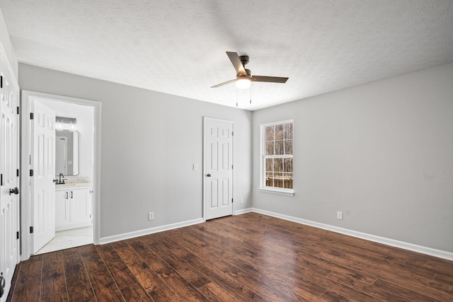 unfurnished bedroom featuring a textured ceiling, baseboards, a sink, and wood finished floors