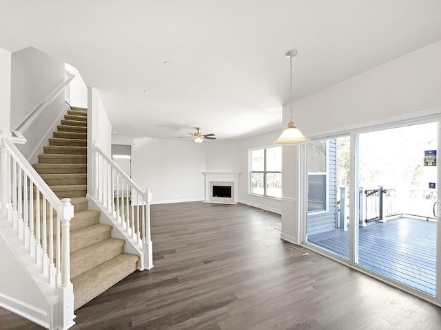 interior space with a fireplace, visible vents, ceiling fan, wood finished floors, and baseboards