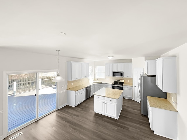 kitchen with visible vents, dark wood-style floors, a center island, stainless steel appliances, and white cabinetry