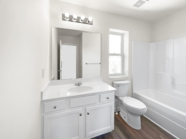 bathroom featuring toilet, wood finished floors, vanity, visible vents, and shower / washtub combination