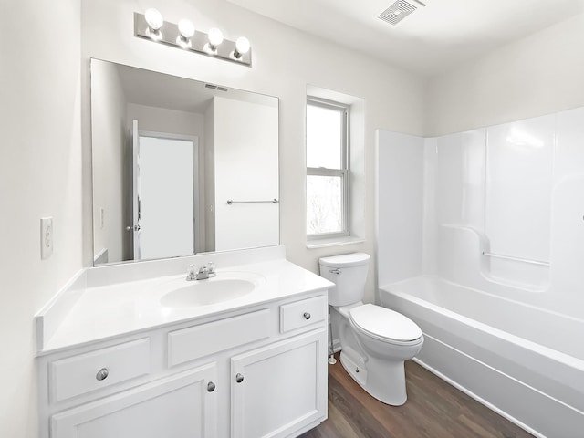 full bath featuring visible vents, toilet, tub / shower combination, vanity, and wood finished floors