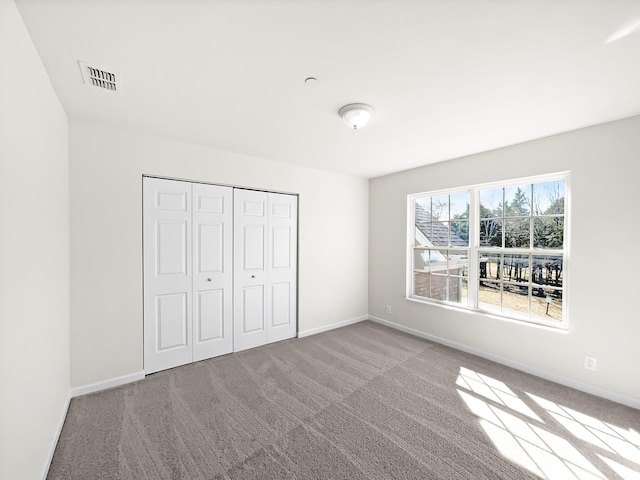 unfurnished bedroom featuring carpet floors, a closet, visible vents, and baseboards