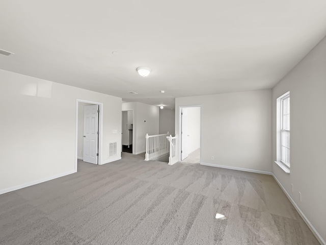 spare room featuring light carpet, visible vents, and baseboards