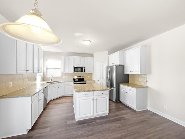 kitchen with stainless steel appliances, a sink, white cabinets, and a center island