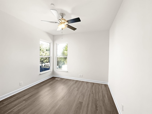 empty room with dark wood-style flooring, visible vents, ceiling fan, and baseboards