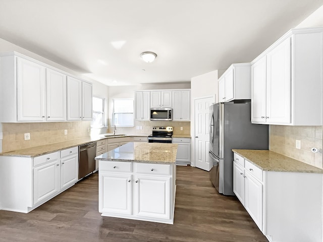 kitchen with appliances with stainless steel finishes, a sink, white cabinets, and a center island