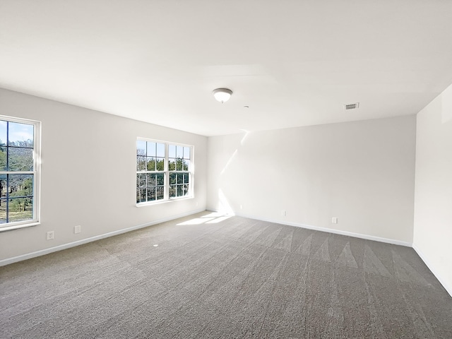 carpeted spare room featuring baseboards and visible vents