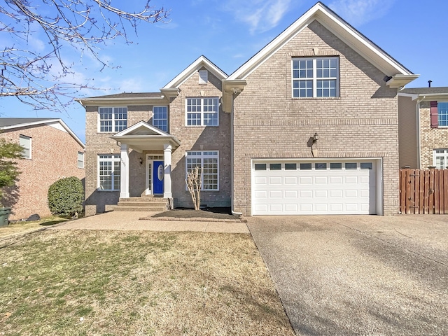 traditional-style home with an attached garage, fence, concrete driveway, and brick siding