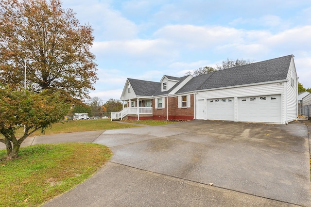 view of front of home with aphalt driveway, a porch, a garage, brick siding, and a front yard