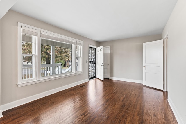 unfurnished bedroom featuring visible vents, baseboards, and dark wood-style flooring