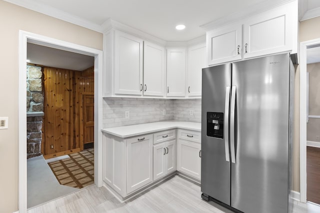 kitchen with light floors, light countertops, backsplash, white cabinetry, and stainless steel fridge with ice dispenser