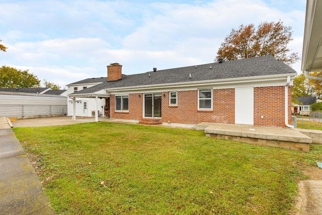 rear view of property with a yard, brick siding, a chimney, and a patio area