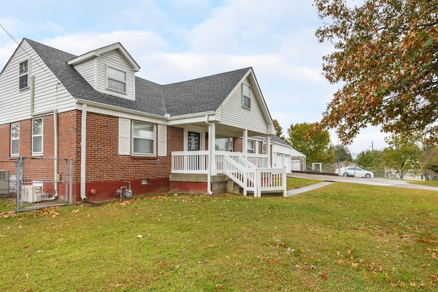 view of front of home featuring brick siding, roof with shingles, covered porch, driveway, and a front lawn