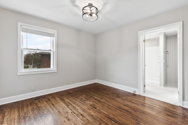 unfurnished room with dark wood-style floors, visible vents, and baseboards