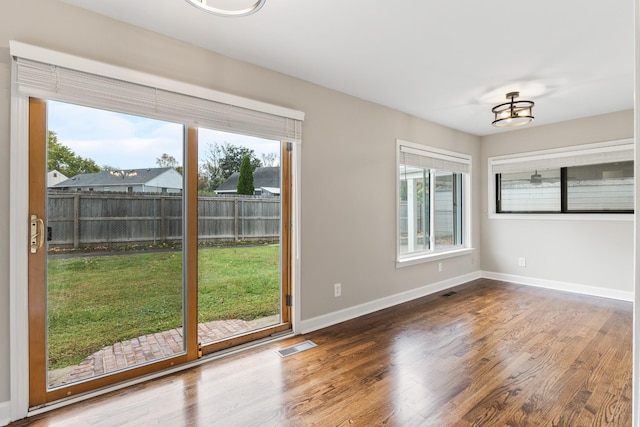 doorway to outside with a healthy amount of sunlight, visible vents, baseboards, and wood finished floors