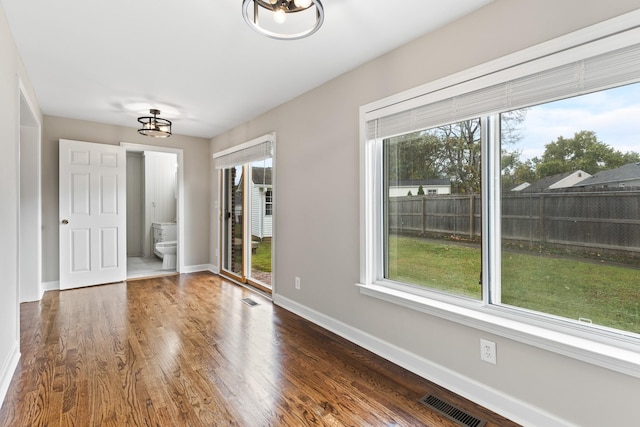 unfurnished bedroom with multiple windows, wood finished floors, and visible vents