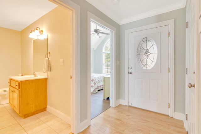 entryway featuring baseboards, vaulted ceiling, light wood-type flooring, and crown molding