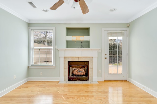 unfurnished living room featuring visible vents, crown molding, baseboards, and wood finished floors