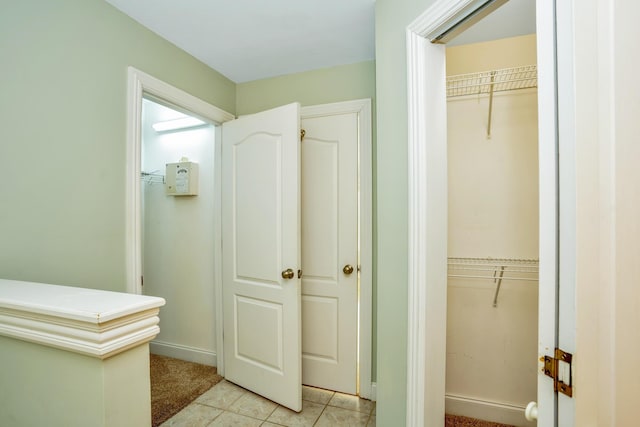 bathroom with a spacious closet, baseboards, and tile patterned floors