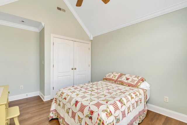 bedroom with a closet, visible vents, ornamental molding, wood finished floors, and baseboards