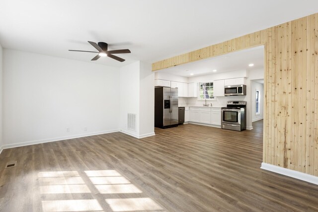 unfurnished living room with dark wood-style floors, a sink, visible vents, and baseboards