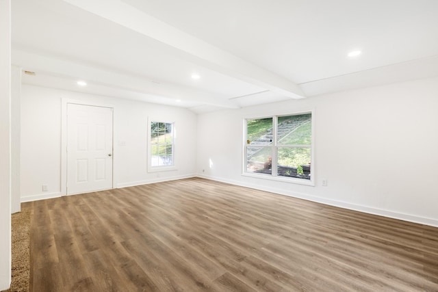 empty room featuring beamed ceiling, baseboards, and wood finished floors