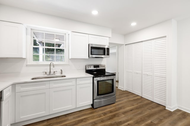 kitchen with white cabinets, dark wood finished floors, stainless steel appliances, a sink, and recessed lighting