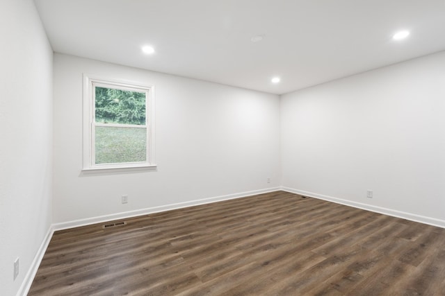 spare room with baseboards, dark wood-type flooring, visible vents, and recessed lighting