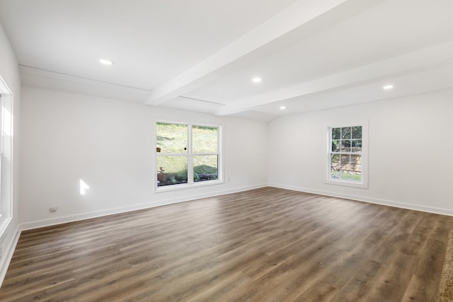 empty room featuring beam ceiling, a healthy amount of sunlight, and baseboards