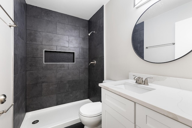 bathroom with tiled shower, vanity, and toilet