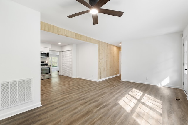 spare room with a ceiling fan, dark wood-style flooring, visible vents, and baseboards