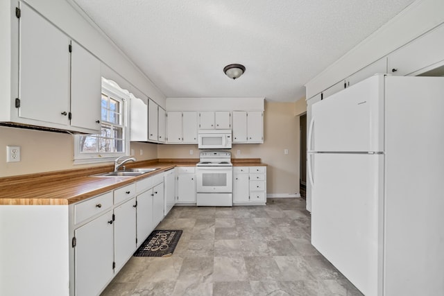 kitchen with white appliances, a textured ceiling, white cabinets, and a sink